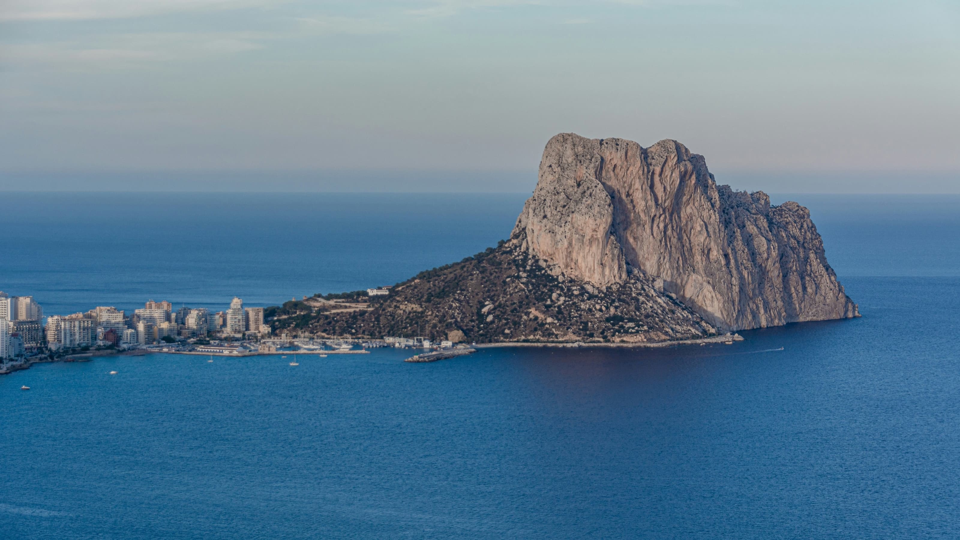 The Peñón de Ifach rising from the sea at dusk, with Calp’s harbour and town to its left
