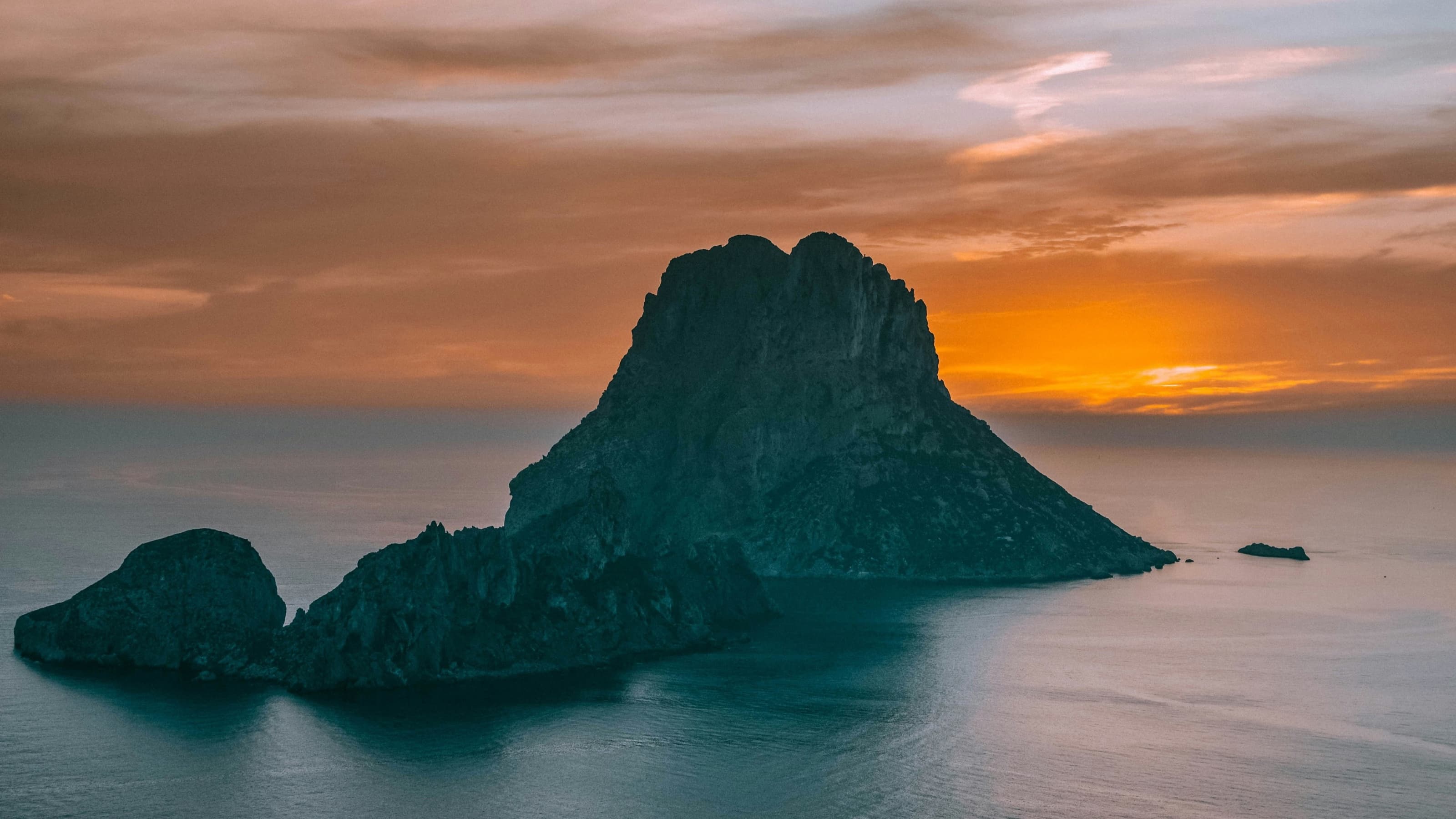 La silueta de es Vedrà recortada contra un atardecer naranja