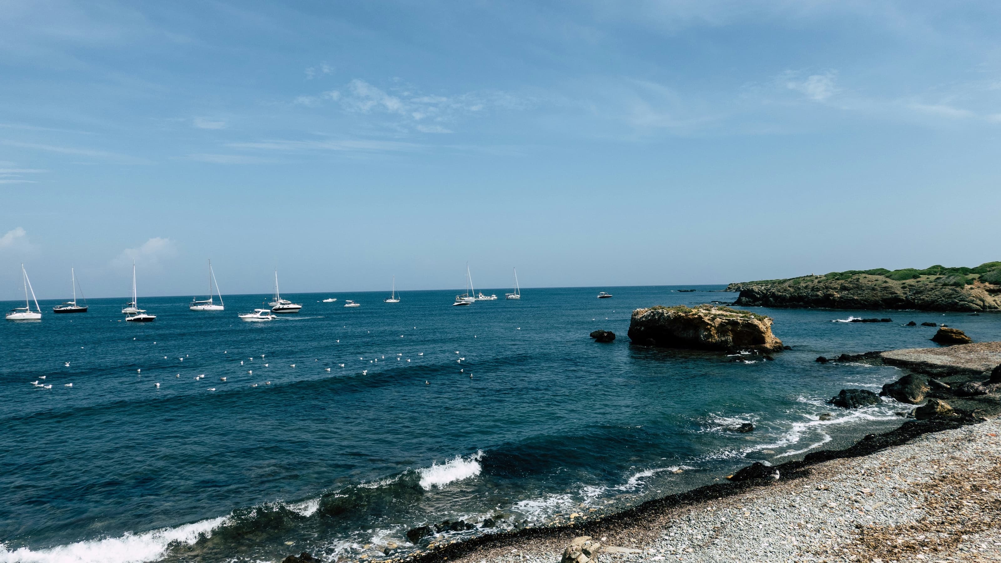 Veleros fondeados frente a la orilla rocosa de la isla de Tabarca en aguas claras
