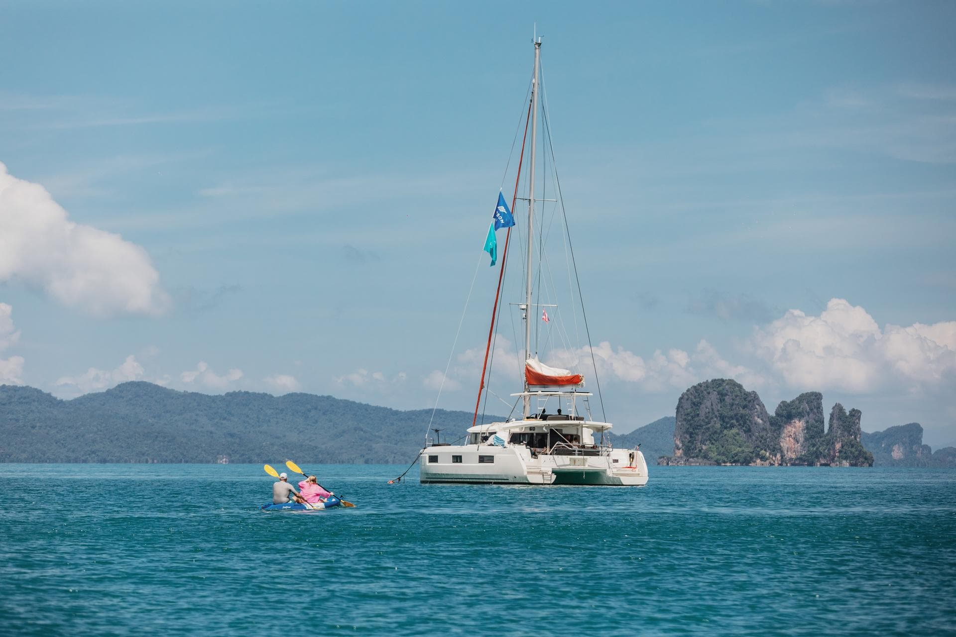 Dos personas en kayak se acercan a un catamarán Lagoon fondeado en una bahía de aguas tranquilas