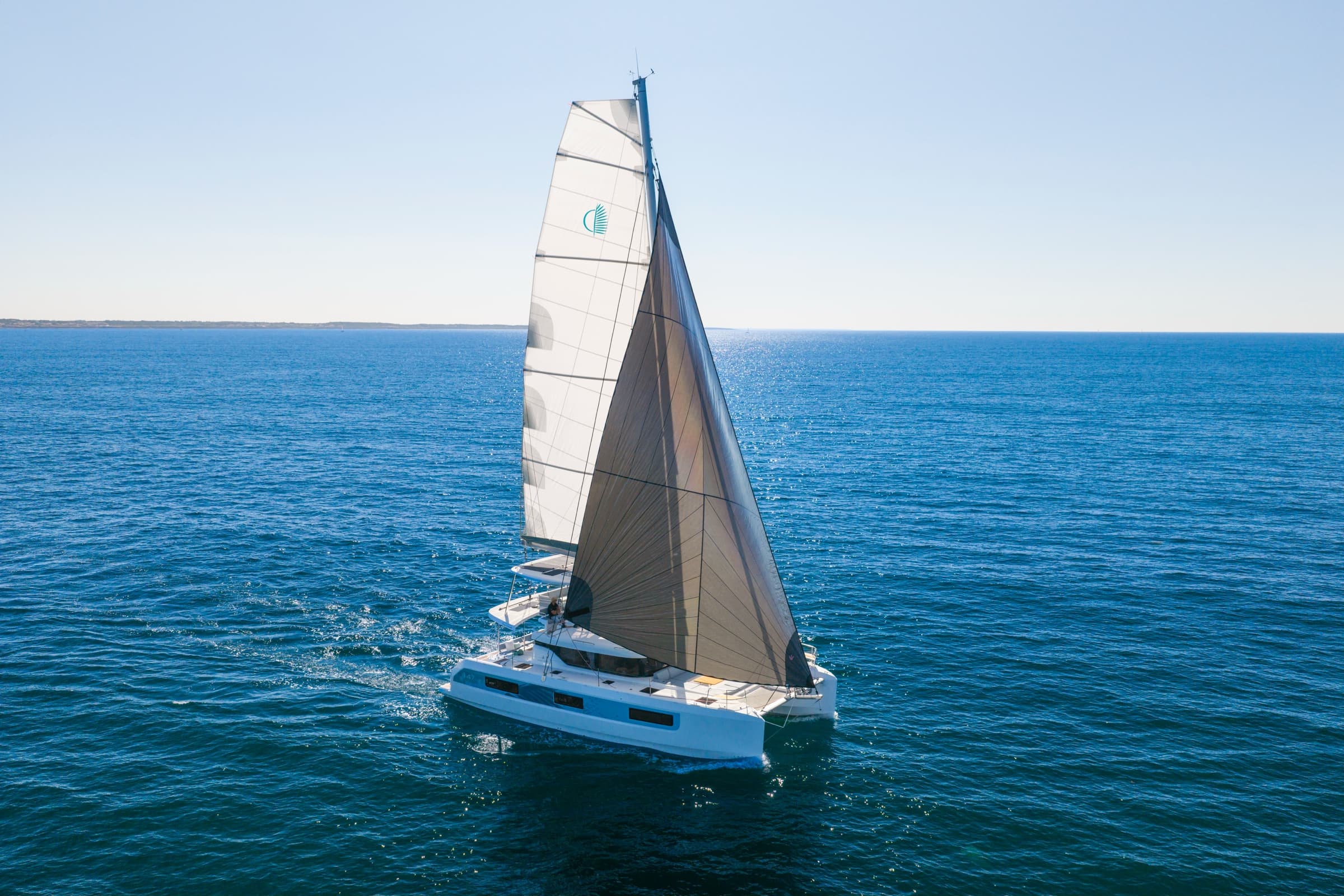 Lagoon 47 under sail in open water, aerial view